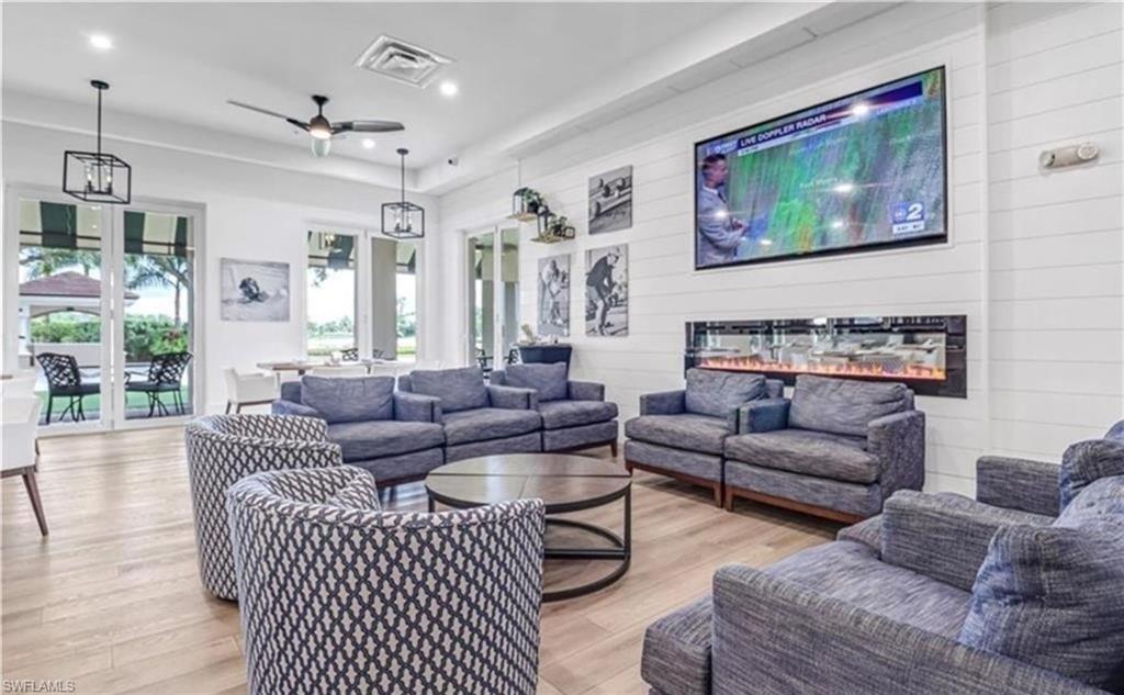 Living room featuring wooden walls, light wood-style floors, a ceiling fan, recessed lighting, and an accent wall
