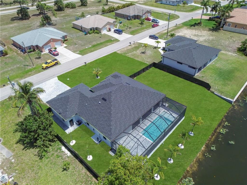 Contemporary home featuring a screened-in pool with a paved deck, dark shingle roof, and a mature palm tree