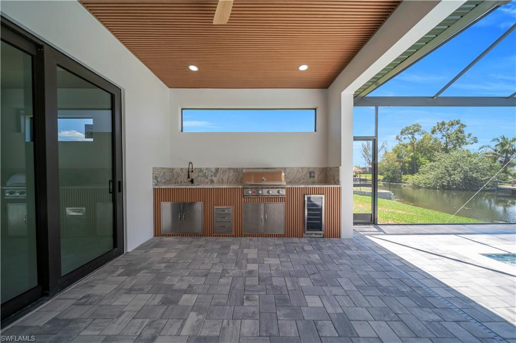 Outdoor kitchen featuring an integrated grill, sink, and beverage refrigerator