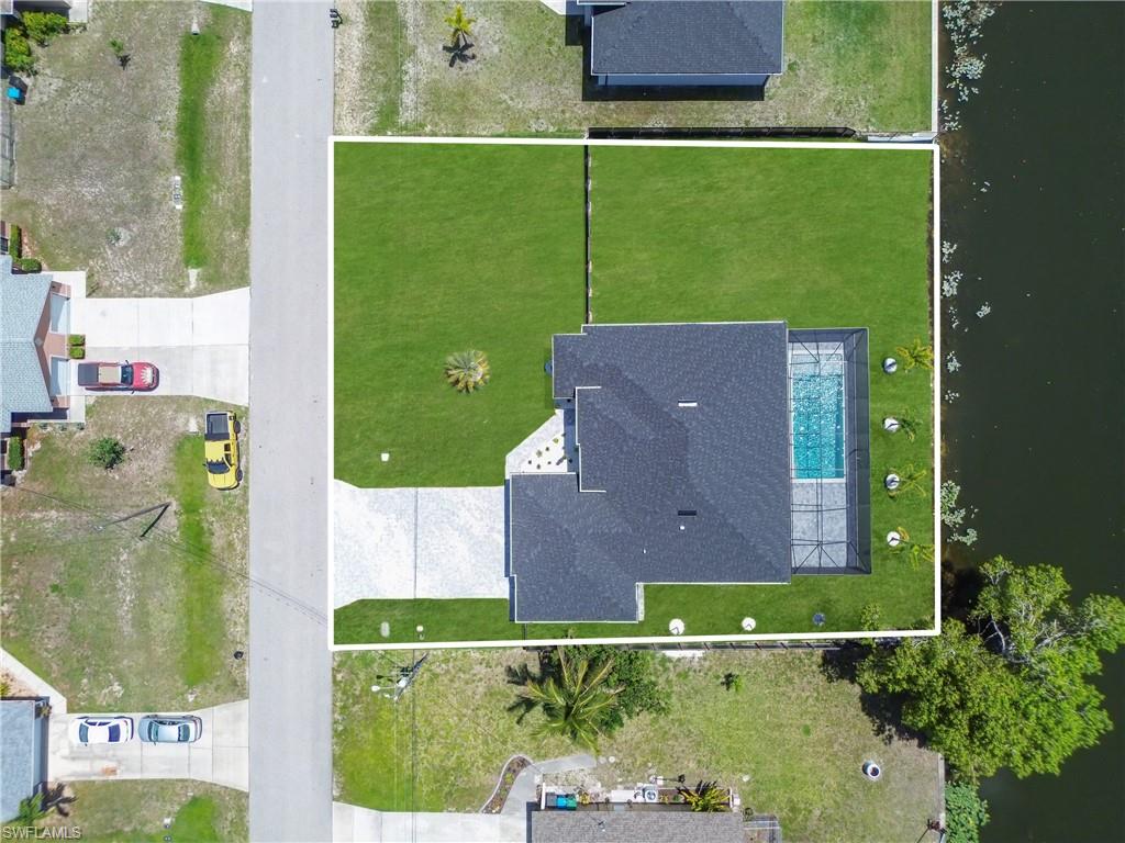 Property featuring a rectangular swimming pool with a screened enclosure, a dark shingle roof, and a paved driveway