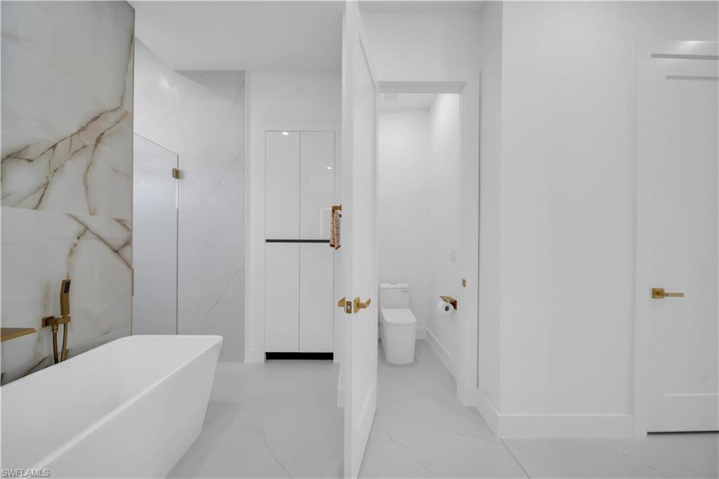 Contemporary bathroom featuring a freestanding tub, a walk-in shower with glass enclosure, large format tile flooring, and integrated storage cabinetry
