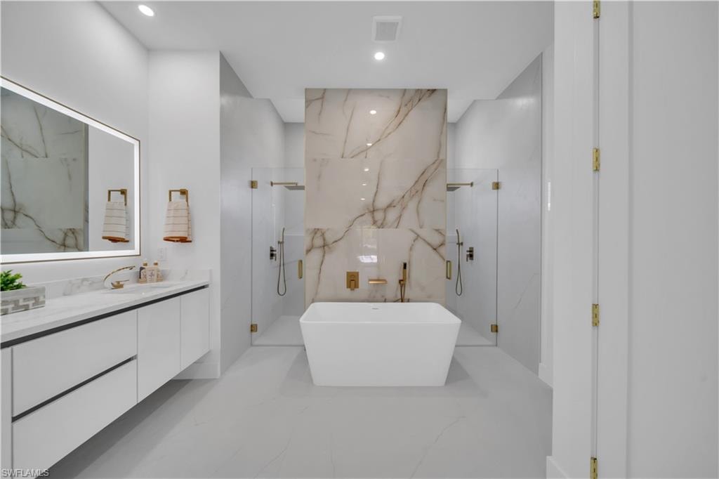 Freestanding rectangular bathtub centered within a spacious bathroom, flanked by two glass-enclosed shower areas