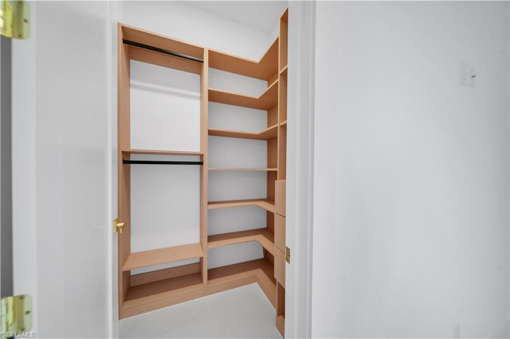 Built-in closet system featuring light wood-finish shelving, multiple hanging rods, and corner storage