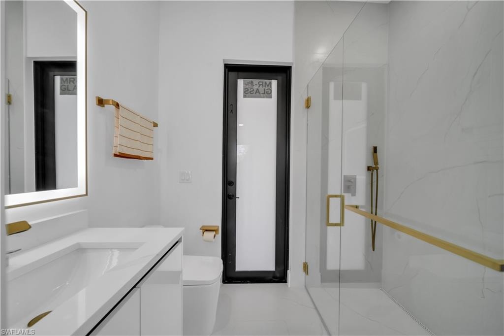 Contemporary bathroom featuring a floating vanity with integrated sink, illuminated mirror, and gold-finish fixtures