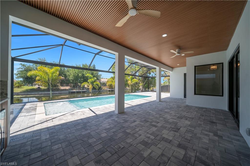 Expansive screened patio featuring paver flooring, a wood-finish slatted ceiling, recessed lighting, and ceiling fans