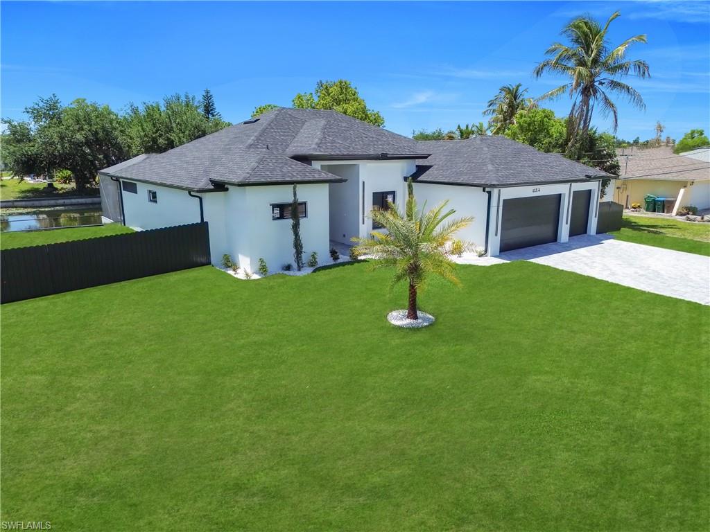 Modern white exterior with a dark shingle roof, two-car garage, and a paver driveway