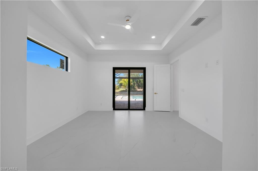 Master Bed room with white walls, light-toned flooring, and a tray ceiling featuring recessed lighting and a ceiling fan