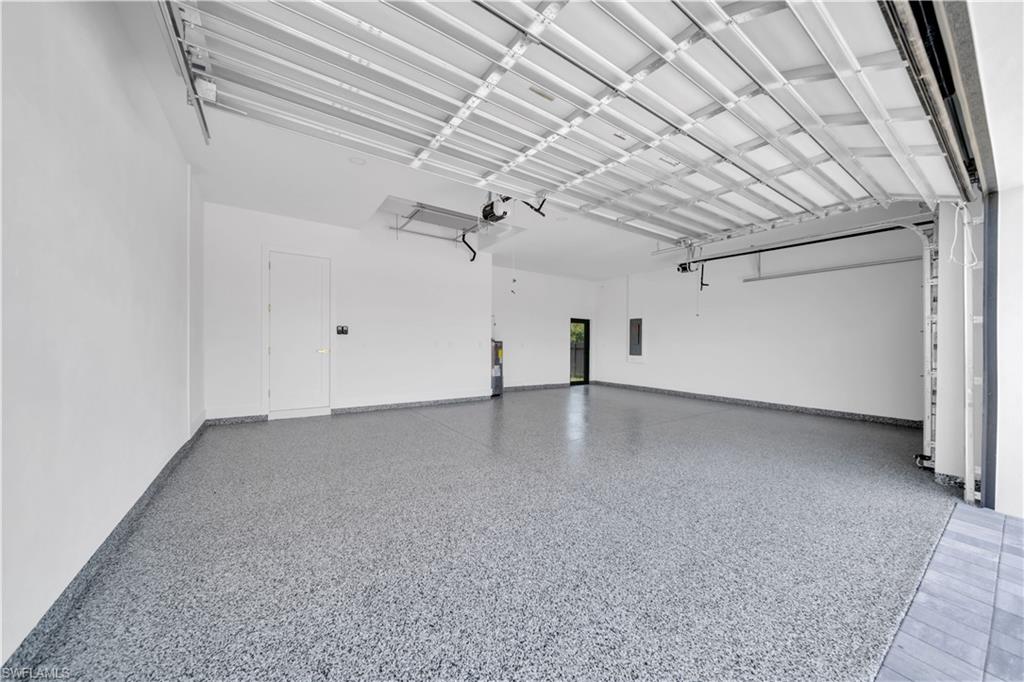 Spacious garage featuring a durable epoxy flake floor finish, white walls, and an overhead garage door mechanism
