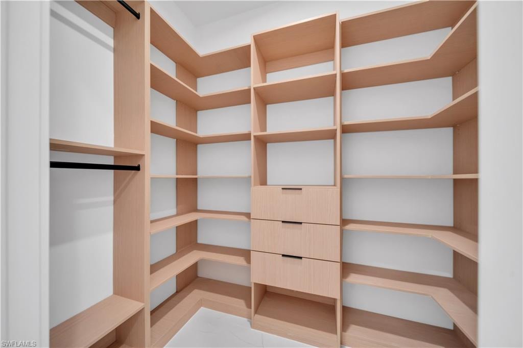 Master Custom closet system featuring light wood-finish shelving, multiple hanging rods, and integrated drawers with sleek hardware