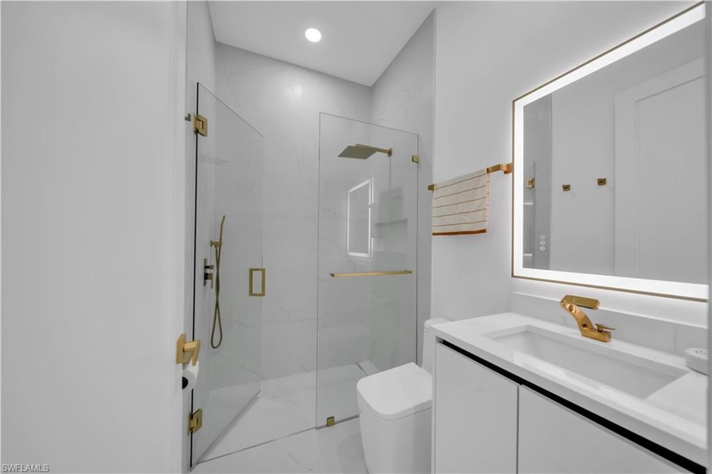 Modern bathroom featuring a frameless glass shower enclosure, a vanity with a rectangular basin, and a backlit mirror