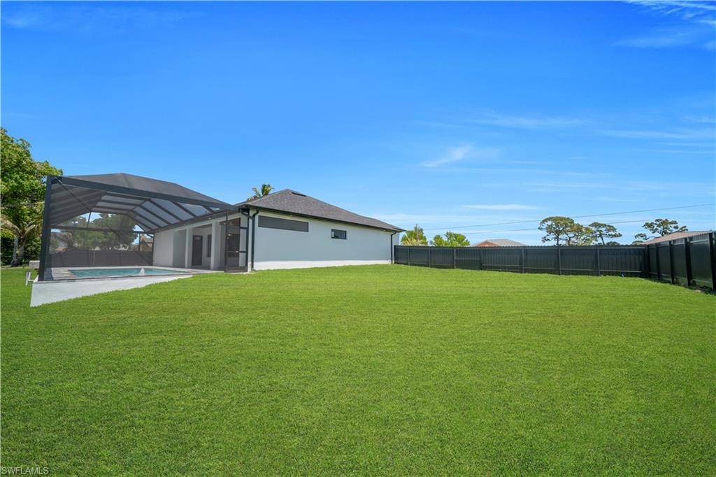 Spacious green lawn with a dark-toned privacy fence
