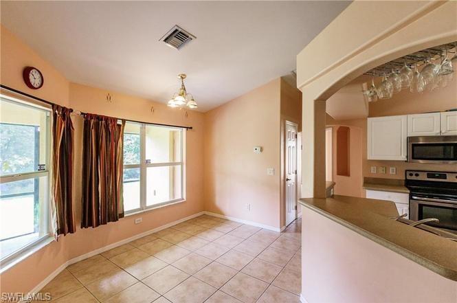 Kitchen featuring a chandelier, appliances with stainless steel finishes, light tile patterned floors, white cabinets, and arched walkways