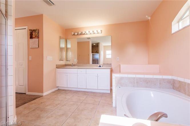 Full bathroom featuring double vanity, a garden tub, plenty of natural light, and light tile patterned floors
