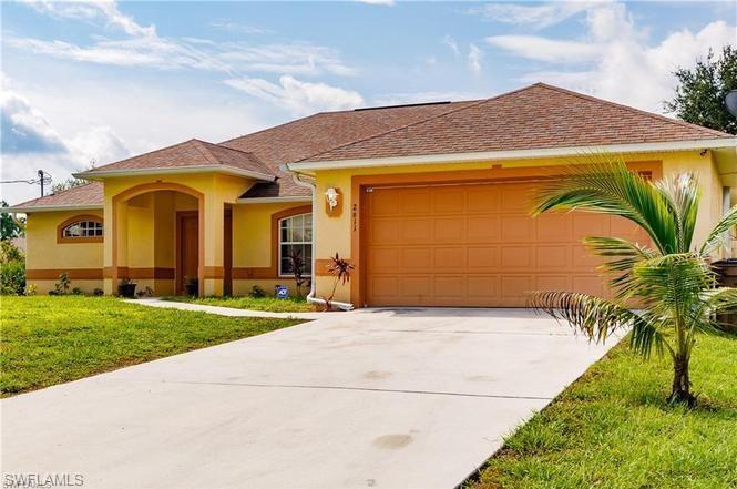 View of front of home with stucco siding, a front lawn, concrete driveway, and a garage