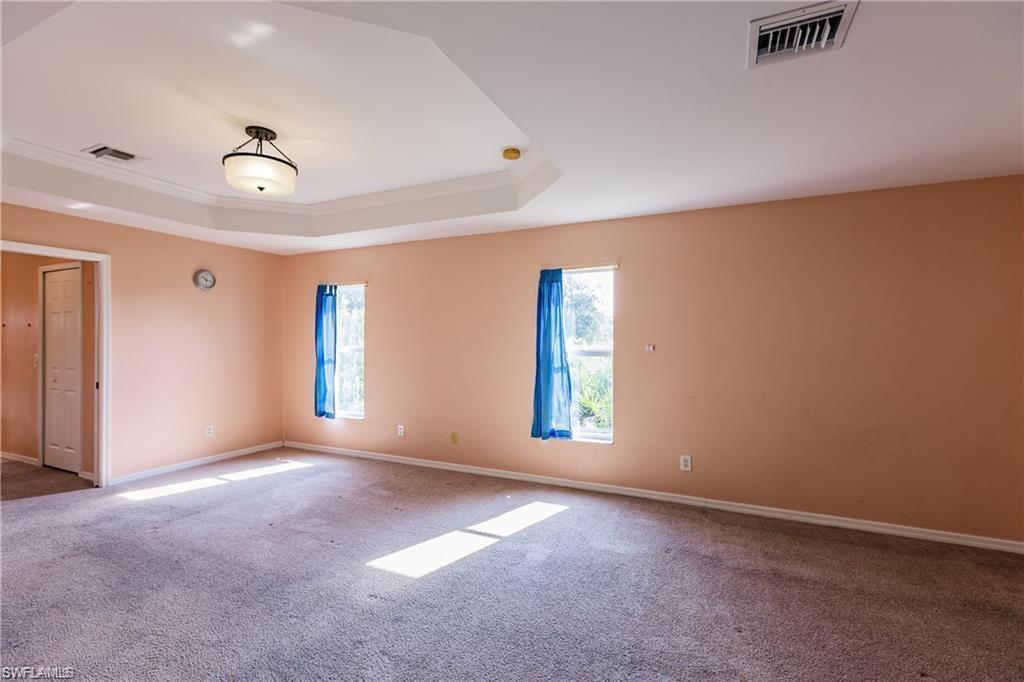 Carpeted spare room featuring ornamental molding and a raised ceiling