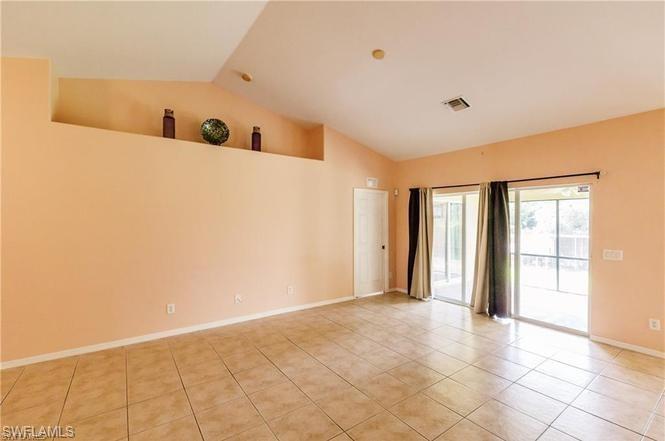 Empty room with light tile patterned floors and high vaulted ceiling