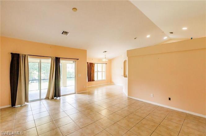 Spare room featuring light tile patterned floors and lofted ceiling