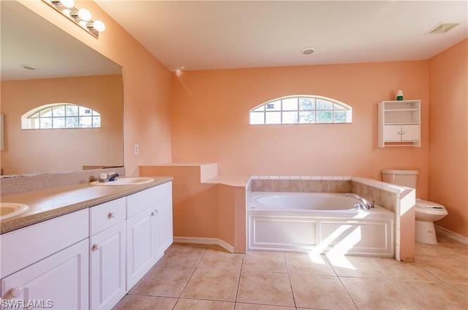 Full bathroom featuring double vanity, a garden tub, and light tile patterned flooring