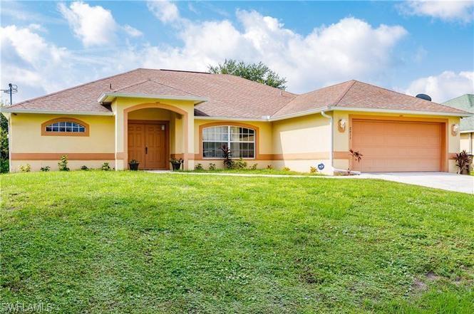 View of front of property with stucco siding, driveway, a front yard, and an attached garage