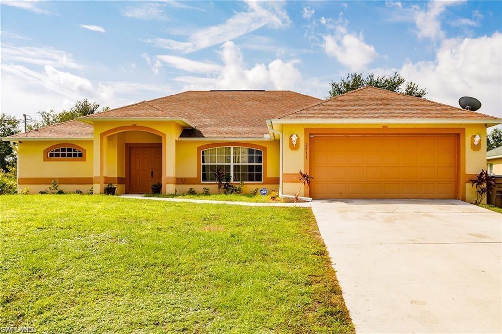 View of front of property featuring stucco siding, concrete driveway, a front lawn, a shingled roof, and a garage