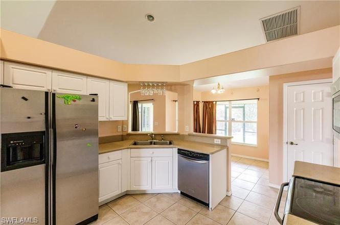 Kitchen with appliances with stainless steel finishes, a peninsula, light tile patterned flooring, white cabinets, and light countertops