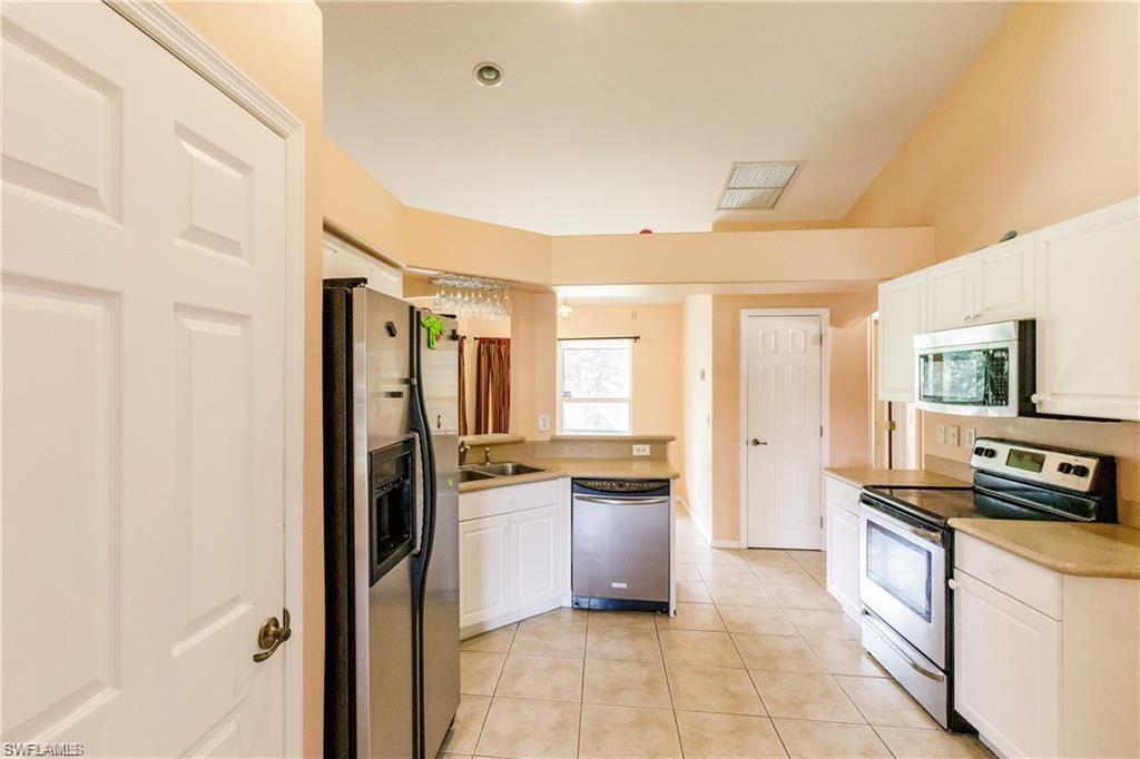 Kitchen featuring stainless steel appliances, light countertops, white cabinets, light tile patterned floors, and a peninsula