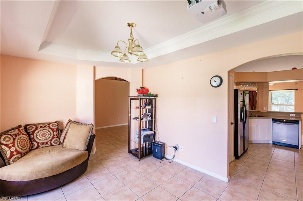 Sitting room featuring arched walkways, light tile patterned flooring, a raised ceiling, and a chandelier
