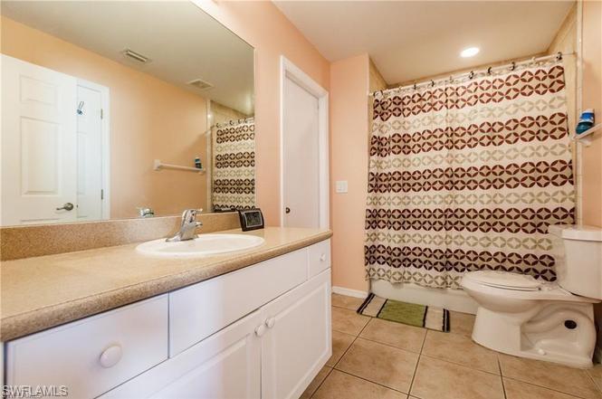 Full bath featuring vanity, light tile patterned flooring, curtained shower, and recessed lighting