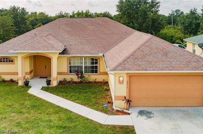 View of front of property featuring a front lawn, an attached garage, stucco siding, and a shingled roof