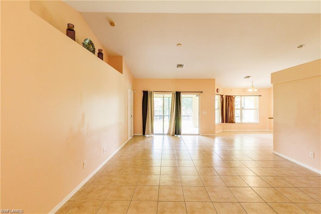 Unfurnished room with light tile patterned flooring, vaulted ceiling, and a chandelier