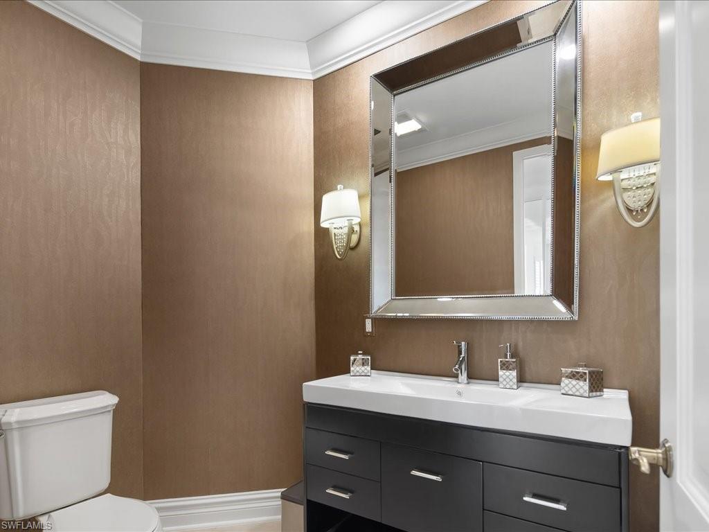 Half bathroom with vanity and ornamental molding