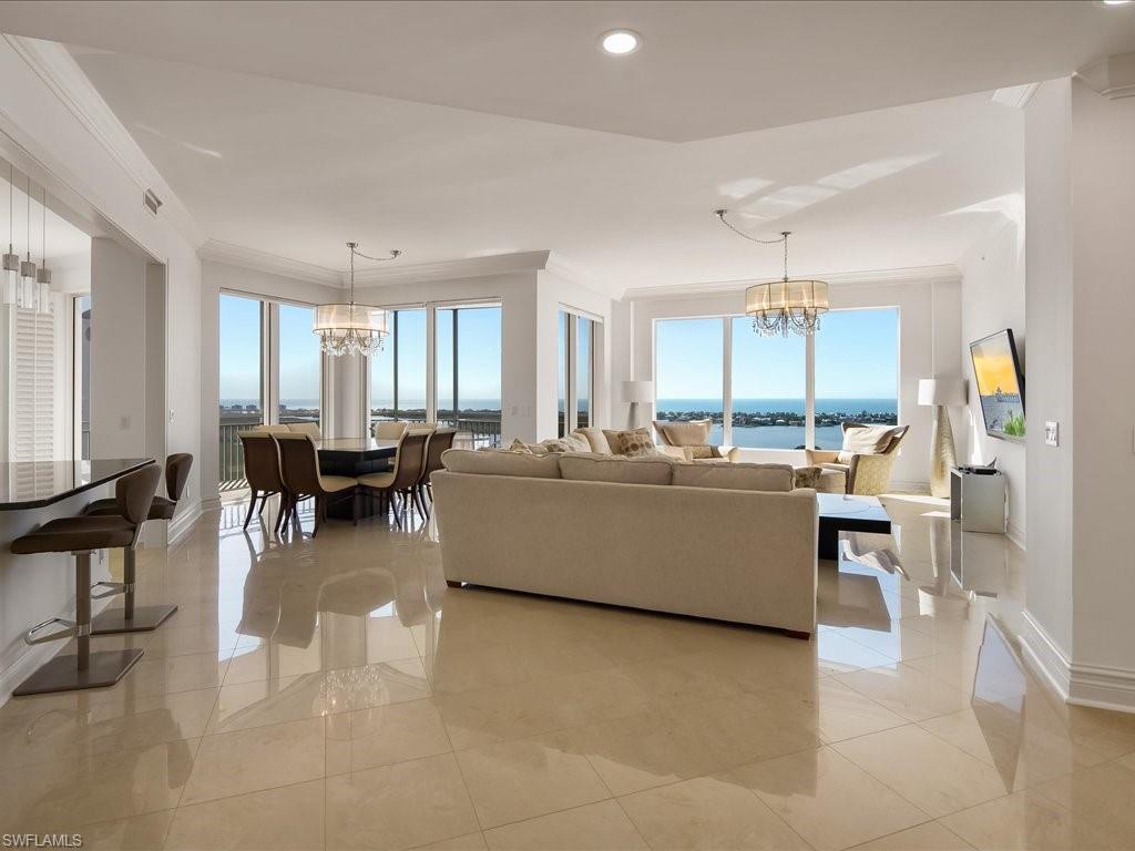 Living room with a chandelier, healthy amount of natural light, recessed lighting, and ornamental molding