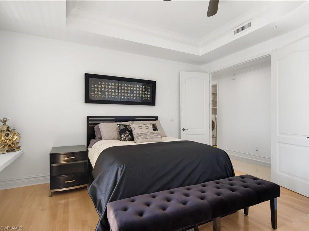 Bedroom with a tray ceiling, light wood-type flooring, ornamental molding, and ceiling fan