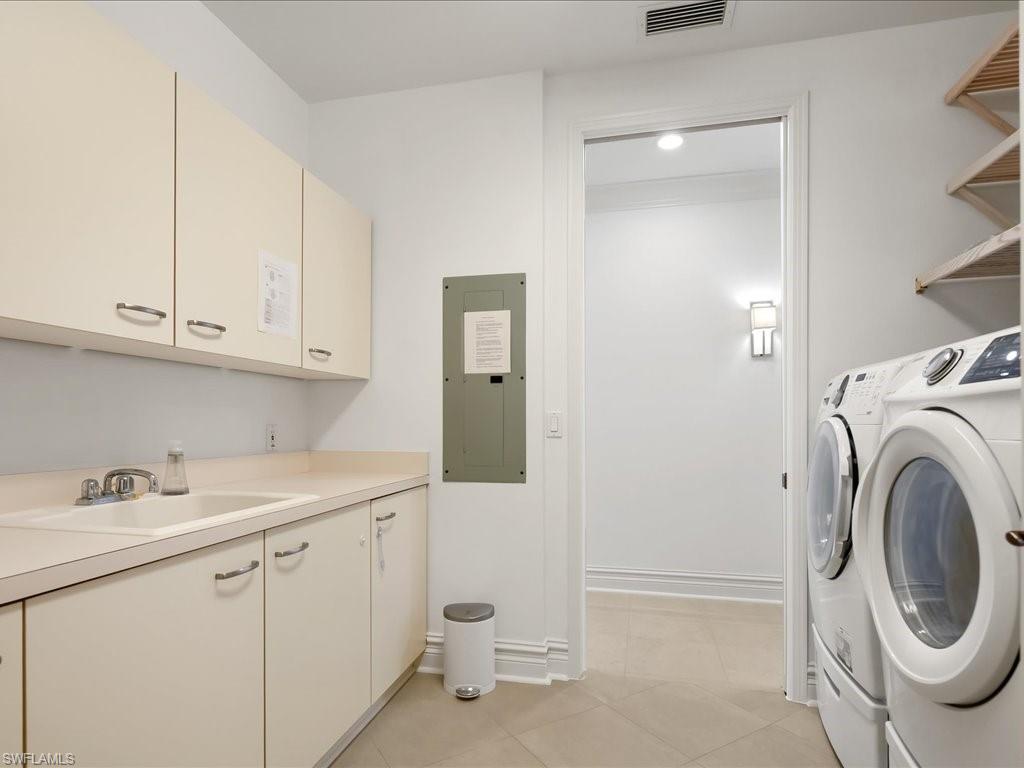 Laundry area featuring electric panel, washing machine and dryer, and light tile patterned floors