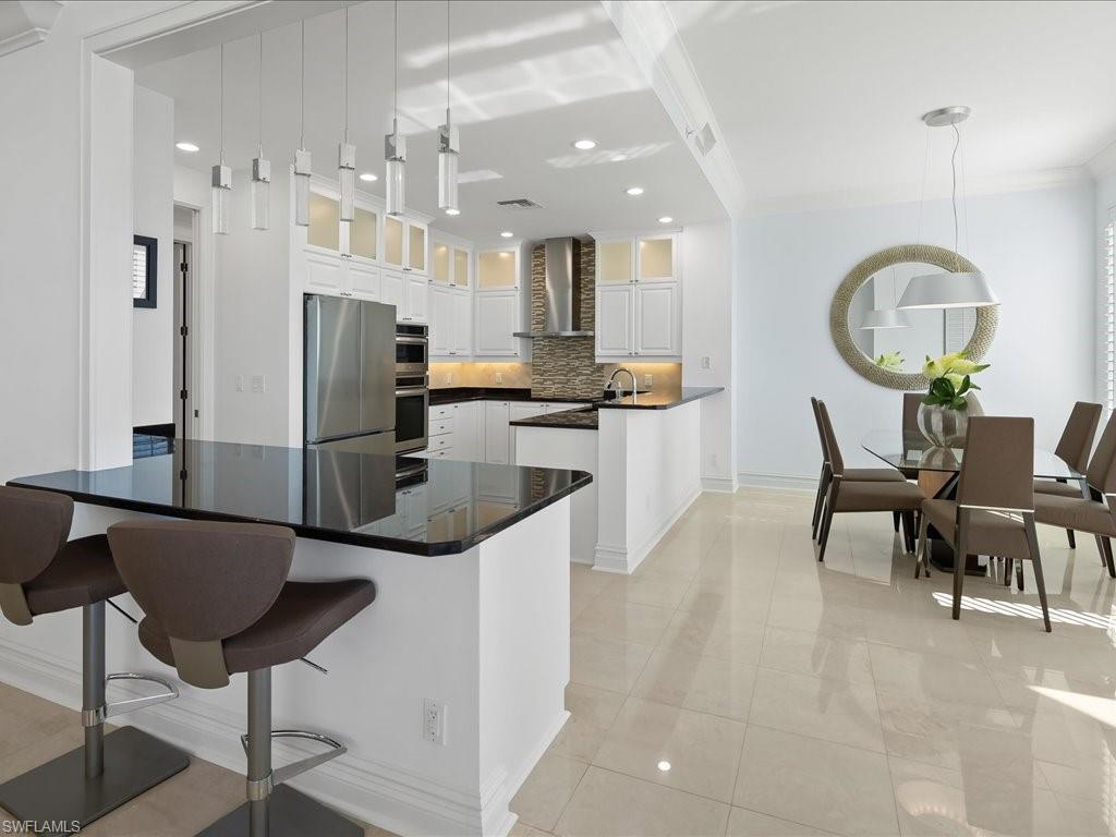 Kitchen with a peninsula, hanging light fixtures, glass insert cabinets, a breakfast bar, and tasteful backsplash