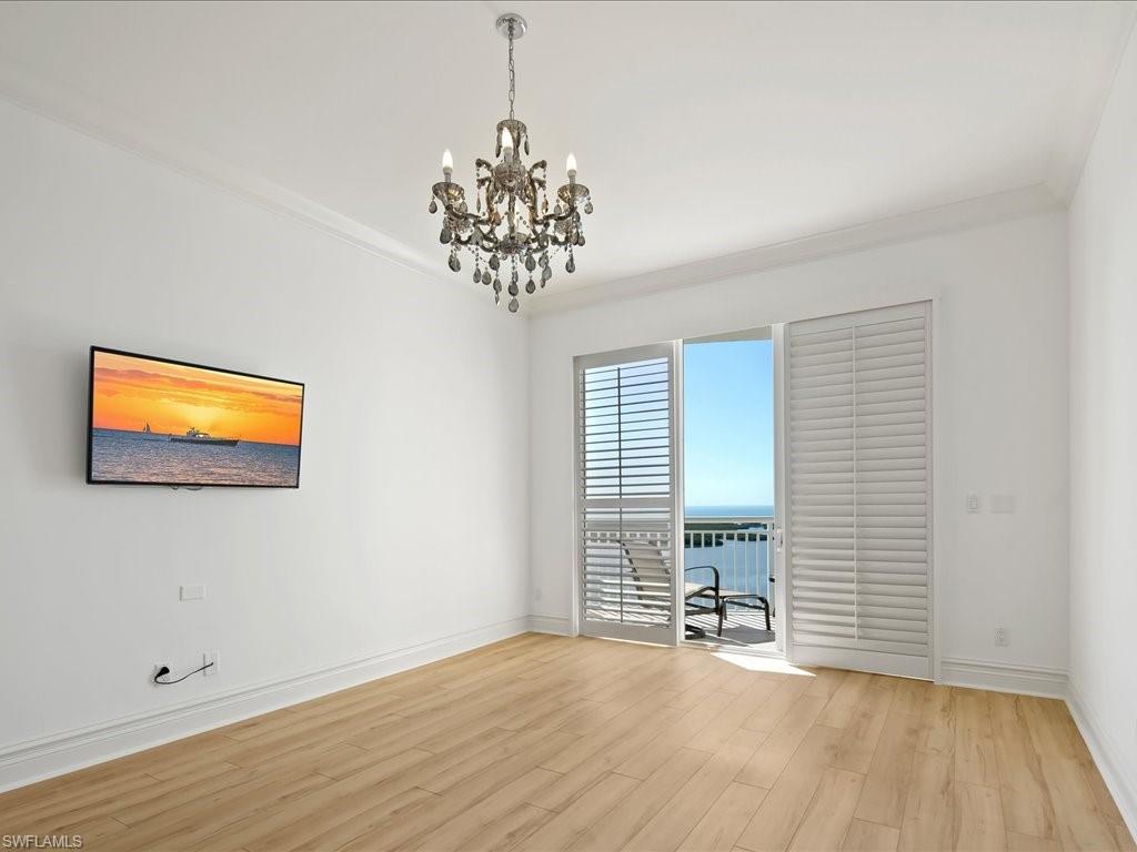 Spare room featuring a water view, light wood-style floors, a chandelier, and crown molding