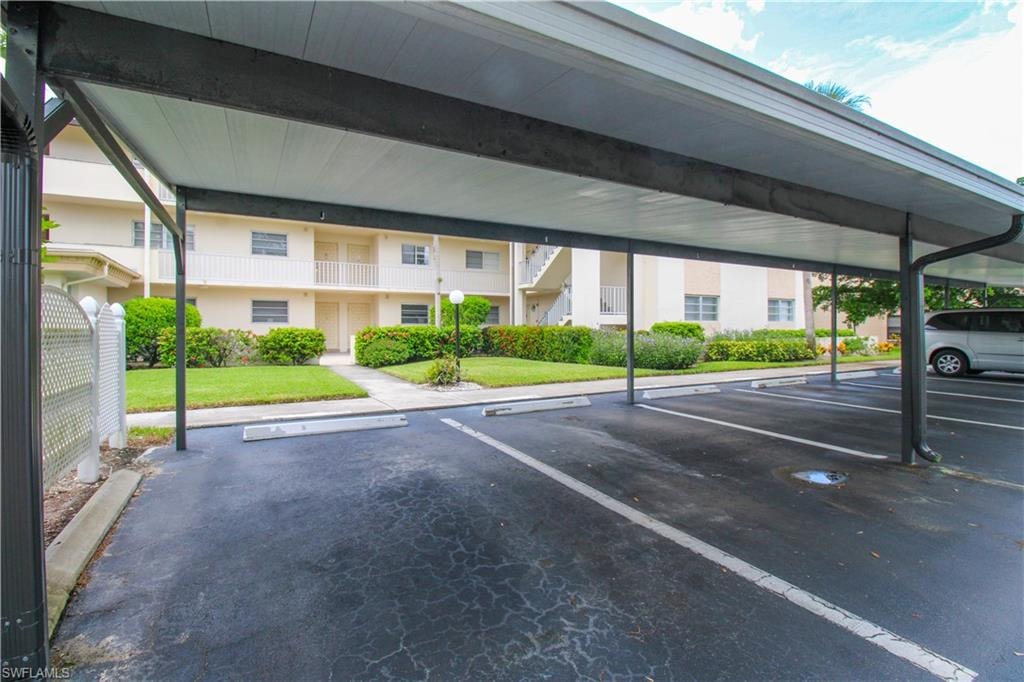 View of parking / parking lot with a yard and a carport