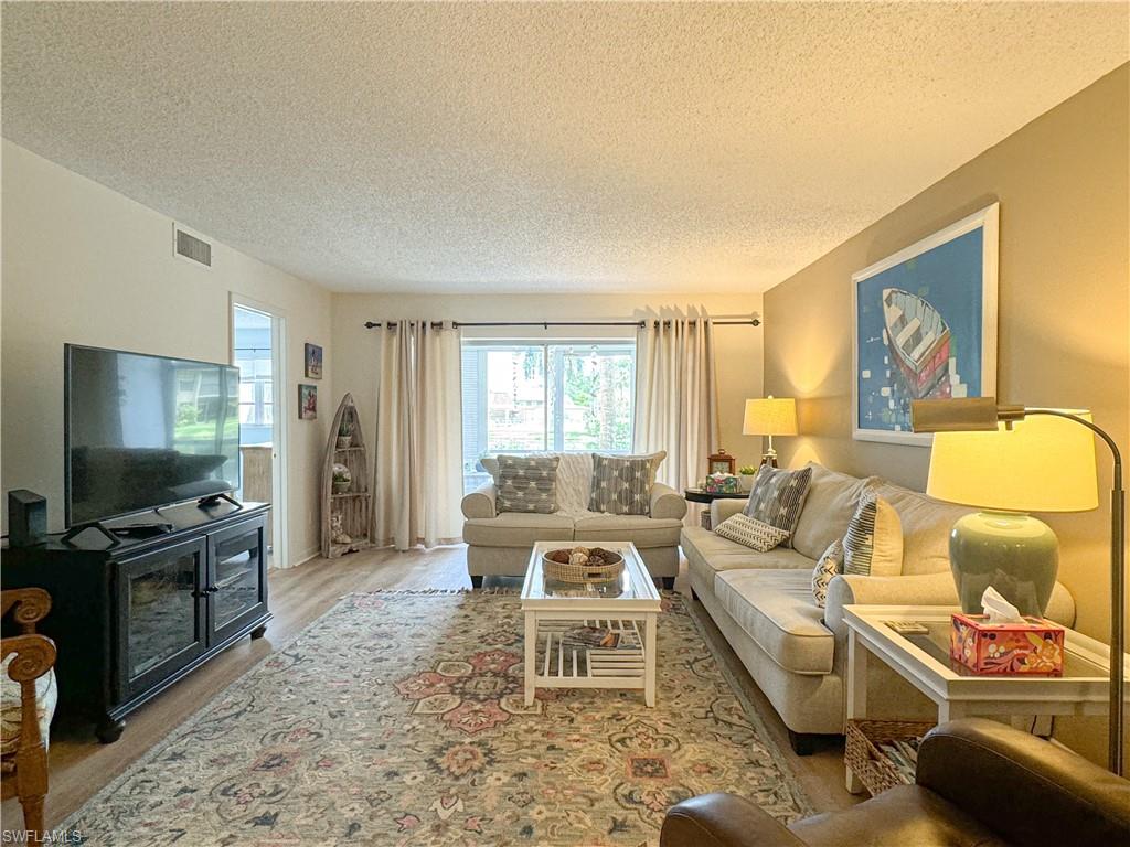Living room with light wood-type flooring and a textured ceiling
