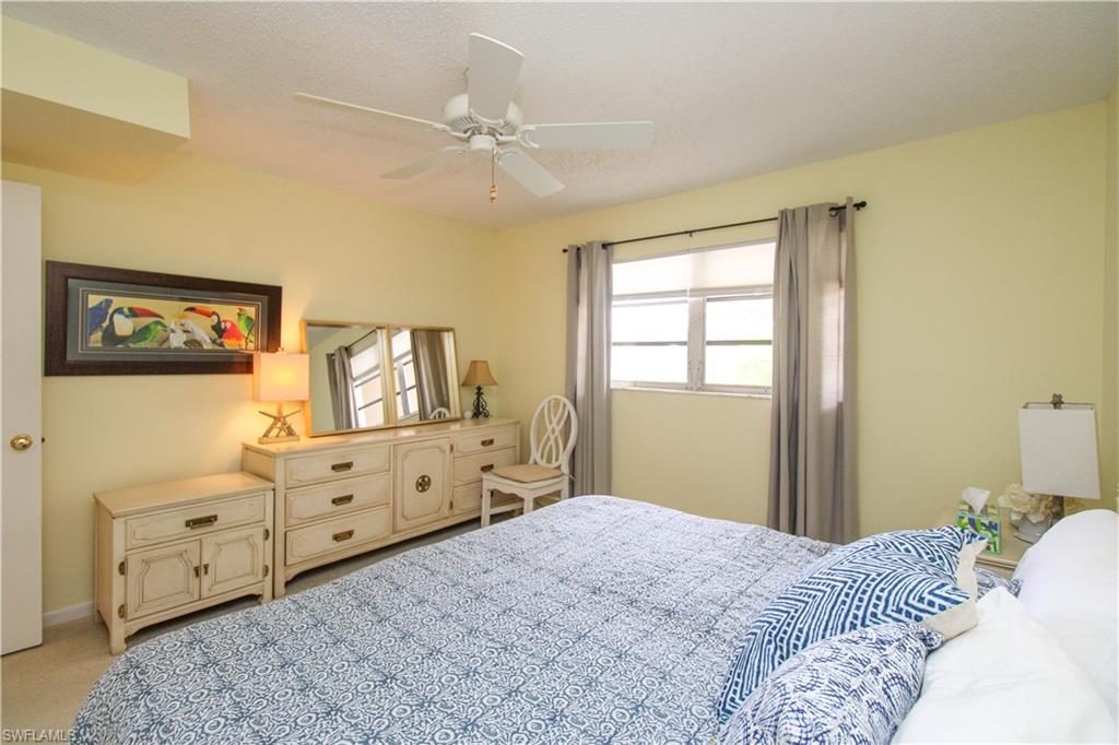 Carpeted bedroom with ceiling fan and multiple windows
