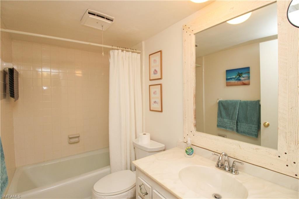 Full bathroom with toilet, vanity, and shower / bath combination with curtain