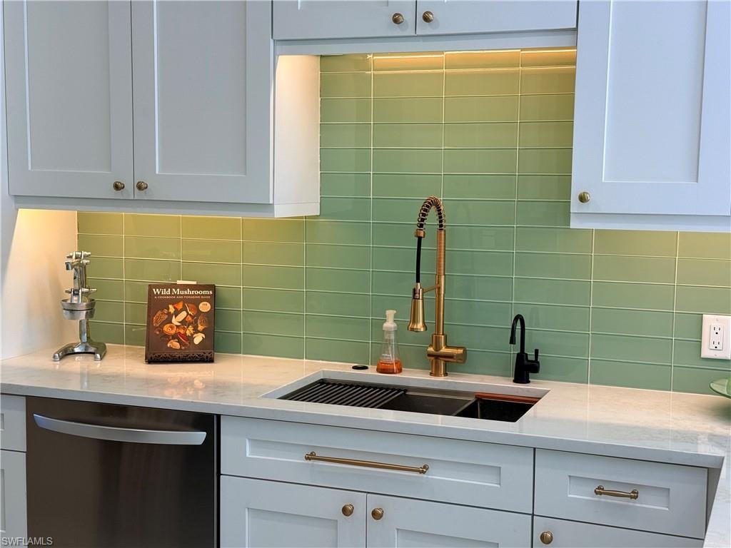 Kitchen with dishwasher, backsplash, and light stone counters