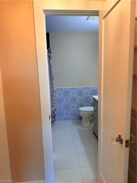 Entrance to Primary Bathroom with vanity, curtained tub, and beautiful Italian tailed walls,  and light tile  flooring