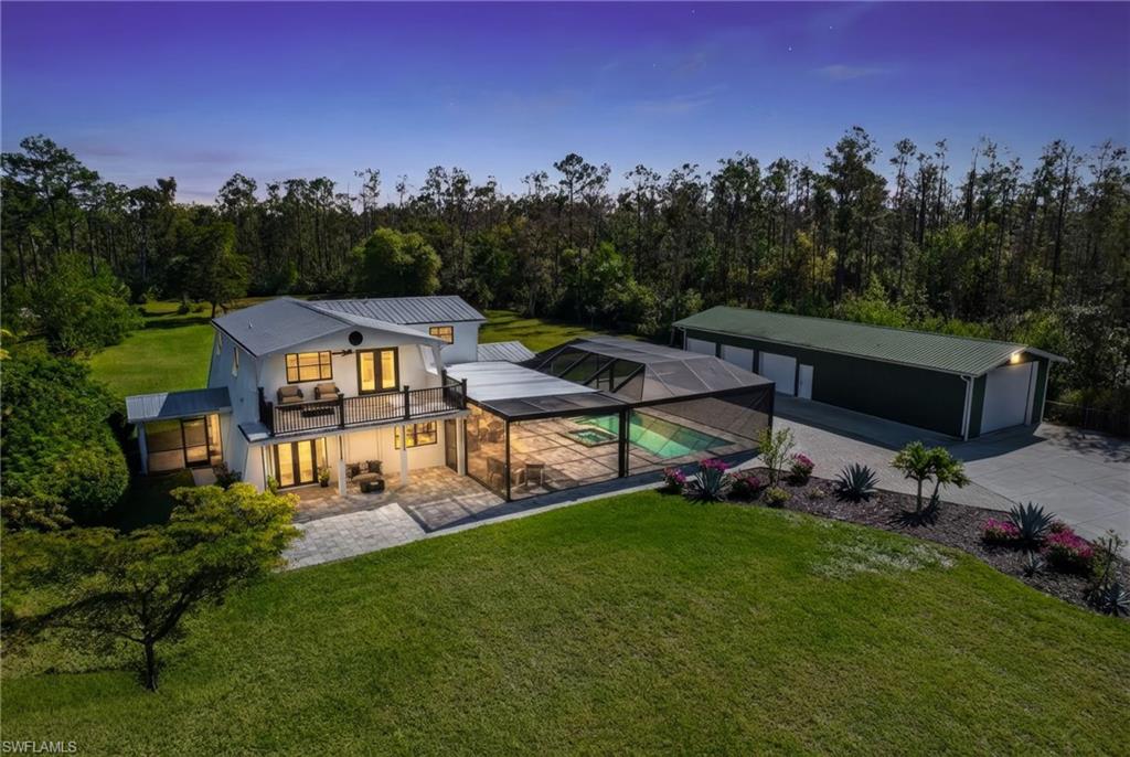 STUNNING twilight aerial highlighting the home’s extensive outdoor living space and detached three-car garage