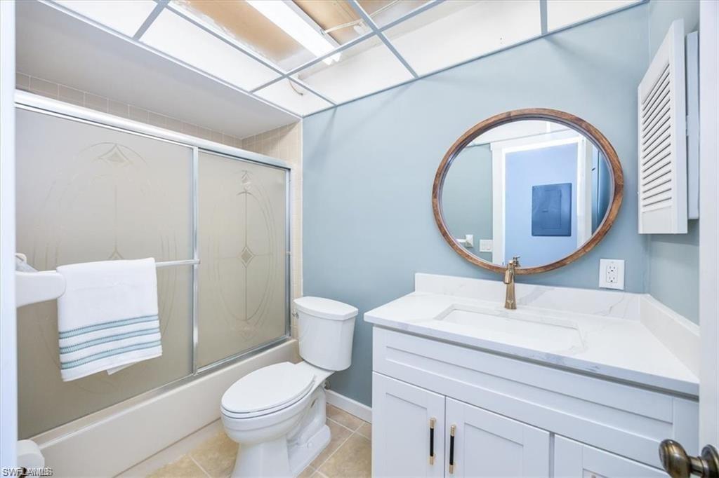 Bathroom with vanity, shower / bath combination with glass door, and light tile patterned floors