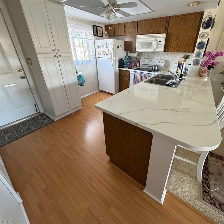 Kitchen with a peninsula, white appliances and ceiling fan