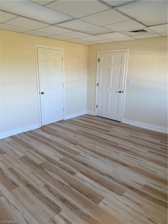Unfurnished bedroom featuring light wood-style floors and a drop ceiling