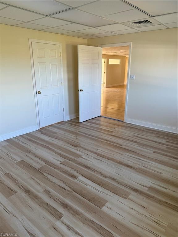 Unfurnished bedroom featuring a drop ceiling and light wood-style flooring