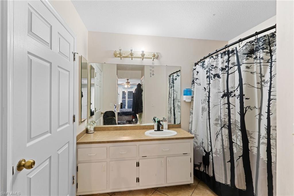 Bathroom with vanity, a shower with curtain, light tile patterned floors, and connected bathroom