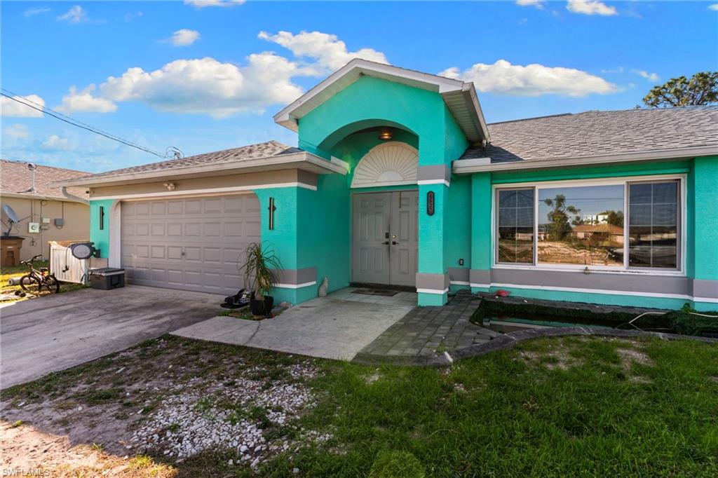 View of front of house with an attached garage, driveway, a front yard, and stucco siding