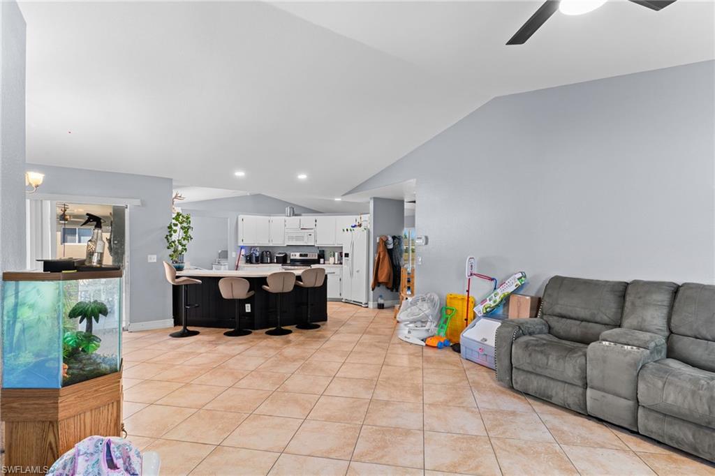 Living room featuring lofted ceiling, a ceiling fan, light tile patterned floors, and recessed lighting